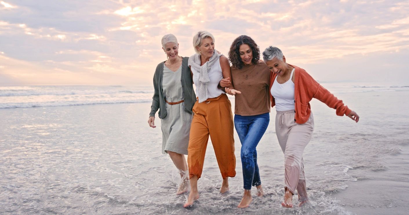 Mature women walking together along the shore at sunset